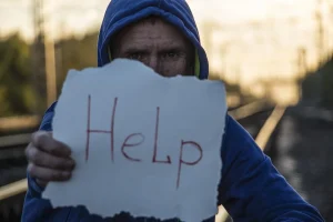 Men holding a paper sign saying 'help'