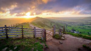 Mam Tor in Peak District, gate and path with sunrise over the hill.