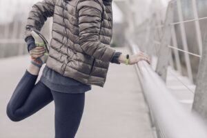 Woman stretching before run in grey coat