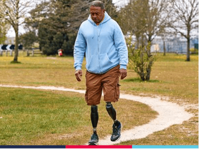 Derek, a wounded serviceman with prosthetic legs, in a blue hoody and brown cargo shorts.